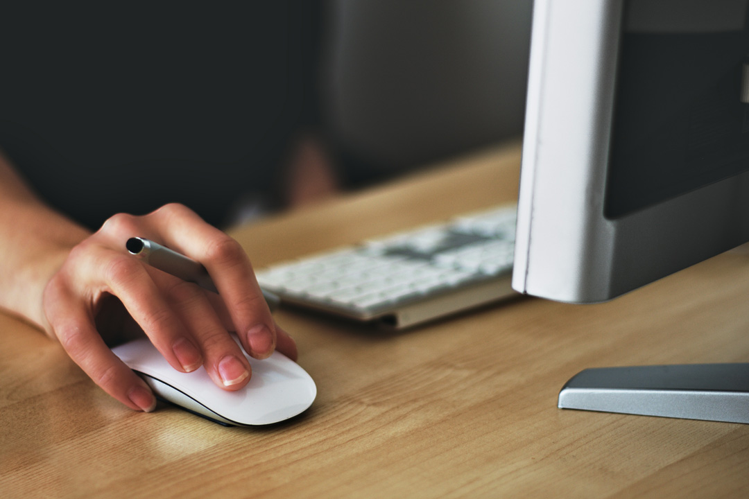 Particolare di mano posata su mouse di persona che lavora al pc