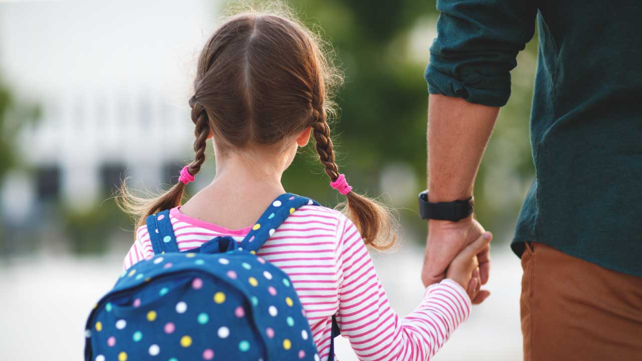 Primo giorno di scuola AGSM AIM, Bambina con zaine che stringe la mano del genitore